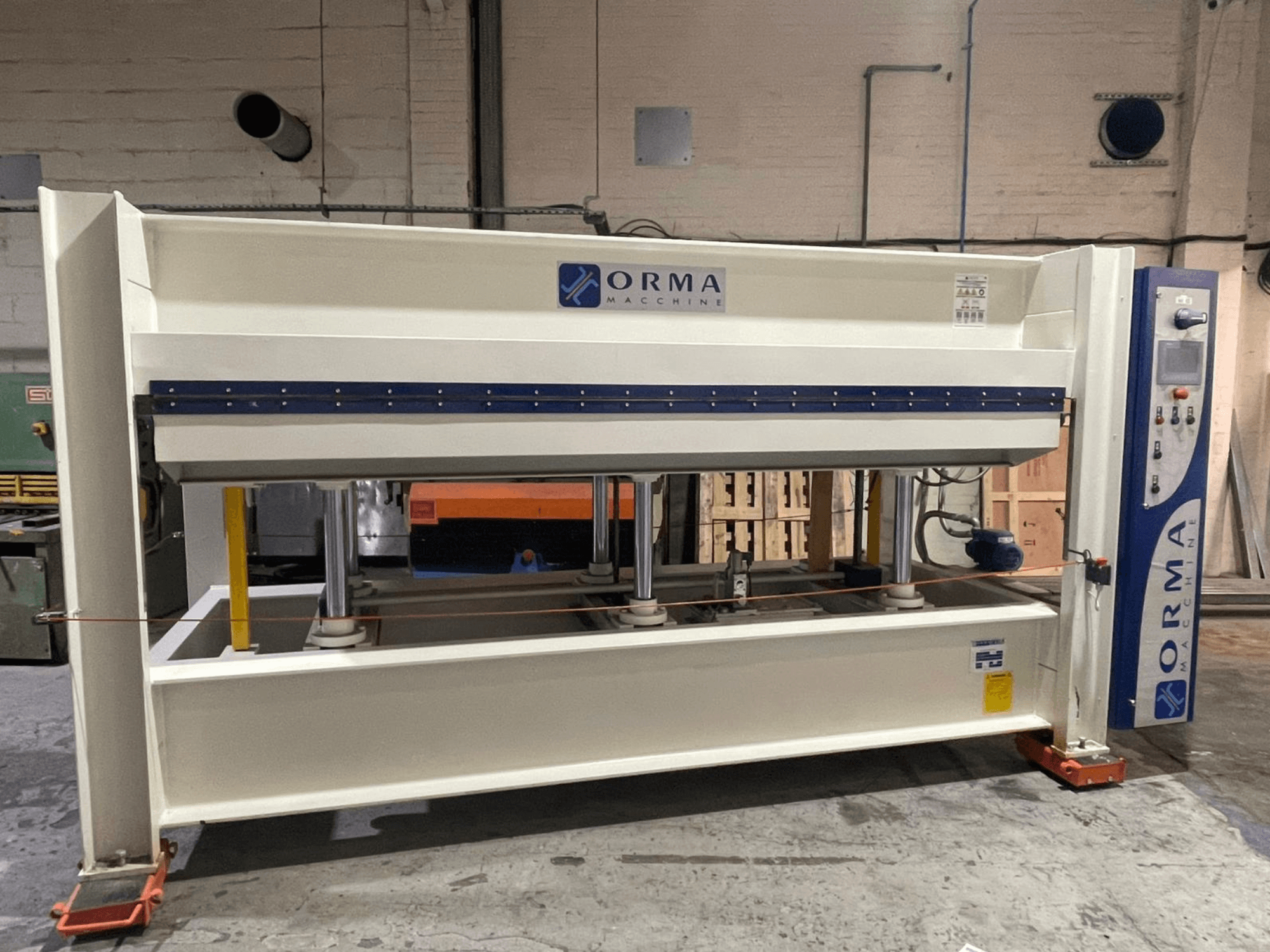 Orma Macchine hüdrauliline press esiplaanil, millel on neli vertikaalset toestust ja paremal pool asuv juhtpaneel.