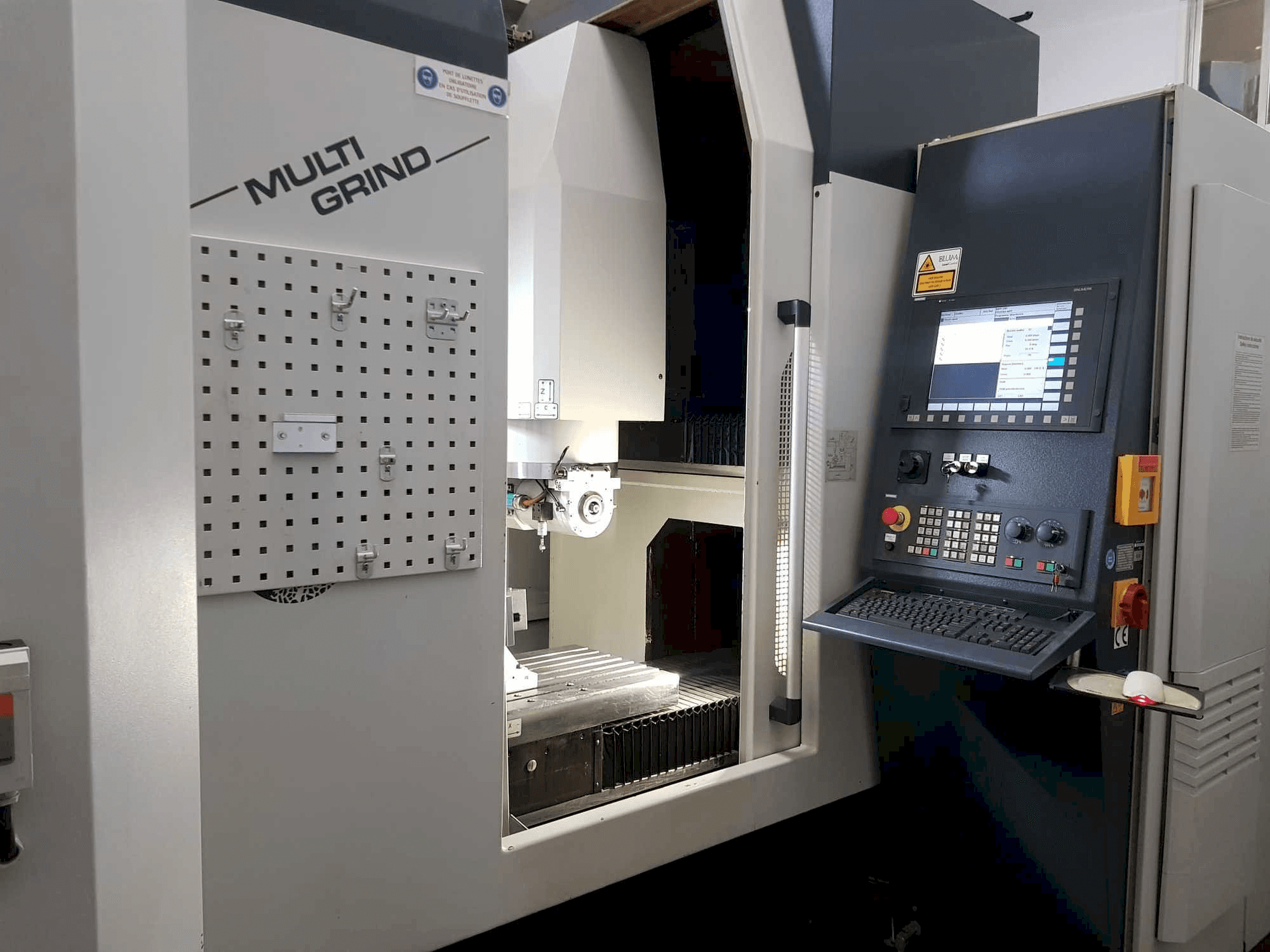 Multi Grind CNC-tööpink eesvaates, millel on juhtpaneel, hoiuplaat ja avatud tööala.